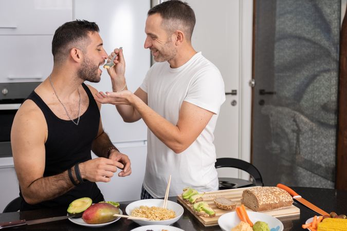 Male couple tasting pasta as they prepare meal