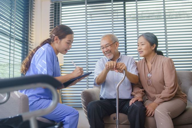Asian nurse doing a check up for smiling older Asian couple at home