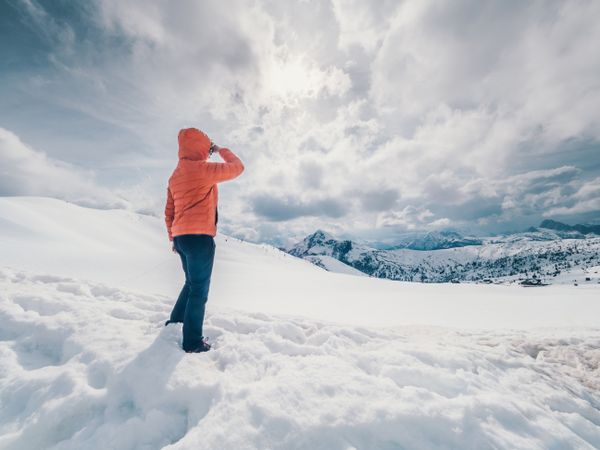 Unrecognizable lonely traveler walking on snowy hill