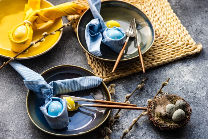 Easter holiday table setting with blue and yellow egg decorations in bowls