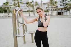 Sportswoman resting after workout in a sandy beach