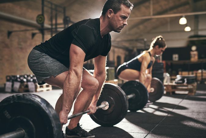 Determined male lifting heavy barbell using body weight