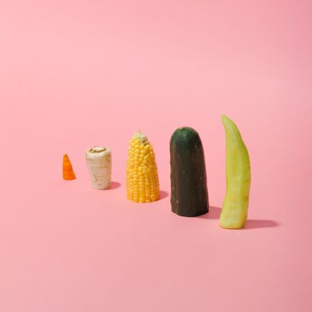 Various vegetables sliced in half on pastel pink background