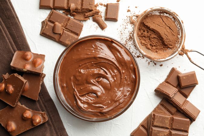 Chocolate, melted chocolate and powder on light background