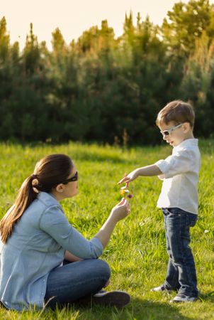 Son giving a bouquet of flowers to his pregnant mother in a field