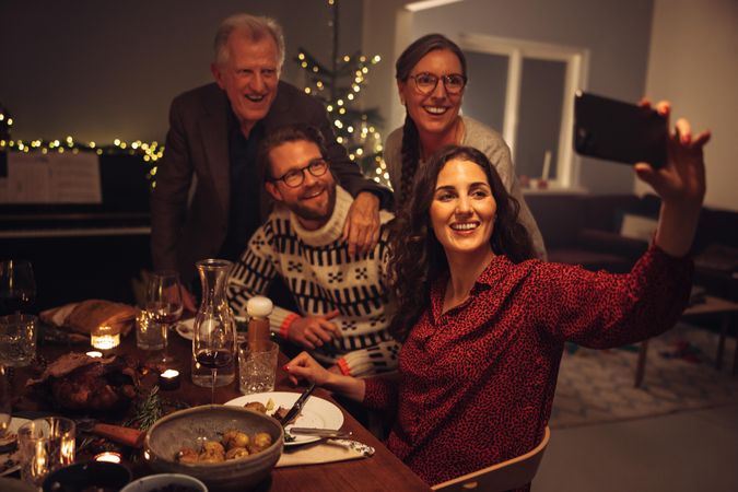 Woman taking selfie with family on Christmas eve at dinner table