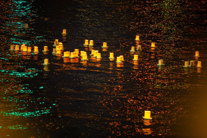 Lit lanterns floating on water at night during Loi Krathong festival