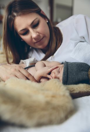 Baby sleeping on a blanket while her mother looks