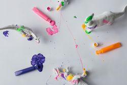 Plastic dinosaur splattered with different colors of paint