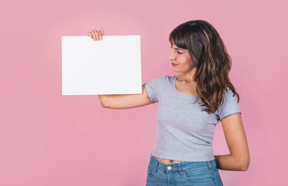 Woman holding a blank sign against a pink background