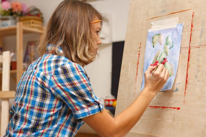 Female artist painting fruit in plaid shirt