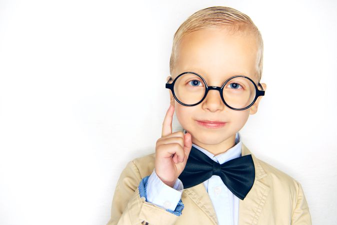 Inquisitive blond boy in glasses and bow tie