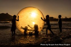 Silhouette of children playing with a huge ball at the Praia da Macumba beach in Rio de Janeiro, Brazil 4BYwP5