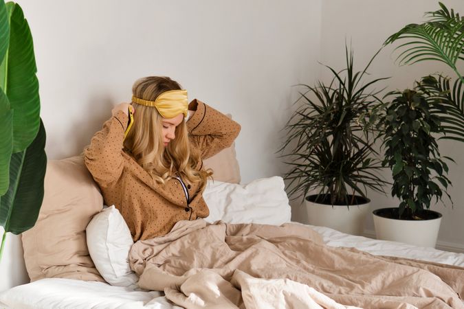 Woman adjusting headband in bedroom.