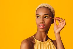 Black woman with short blonde hair applying gold eyeshadow