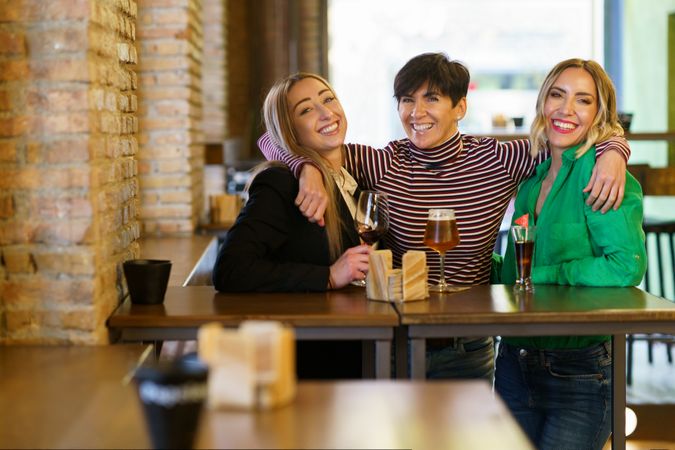 Happy female friends posing for photograph in bar
