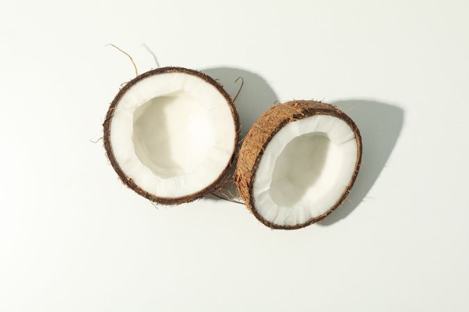 Halves of coconut on plain background, top view