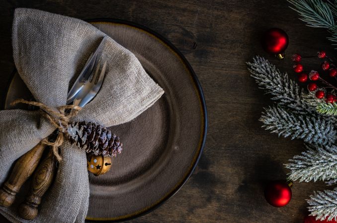 Rustic table setting for Christmas with pine and red baubles