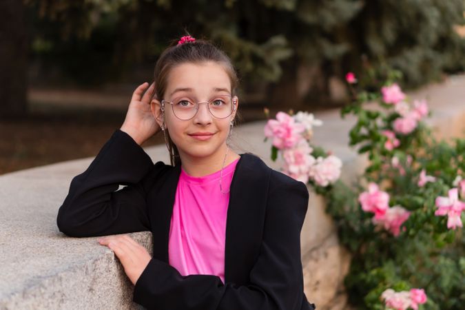 Girl posing confidently near garden of pink flowers