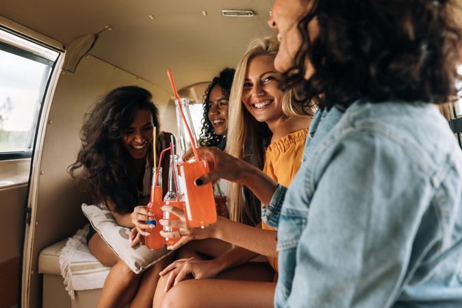 Group of female friends having drinks in the back of a vehicle