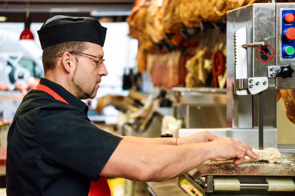 Man in butcher shop slicing meat