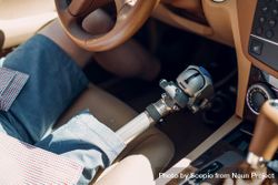 Cropped image of a man with prosthetic leg riding a car 41vj8b