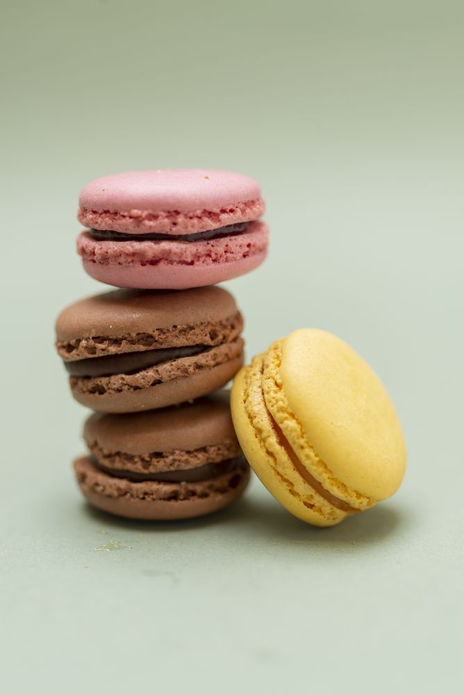 Chocolate, strawberry & lemon macaroons on a green background