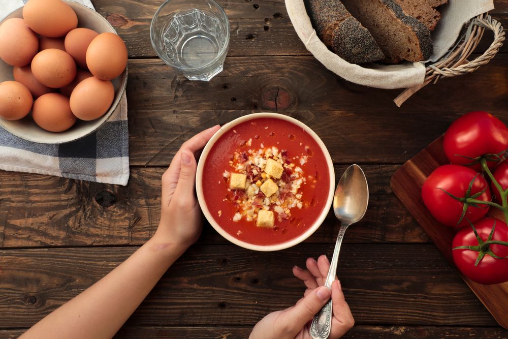 Person hands holding bowl with gazpacho