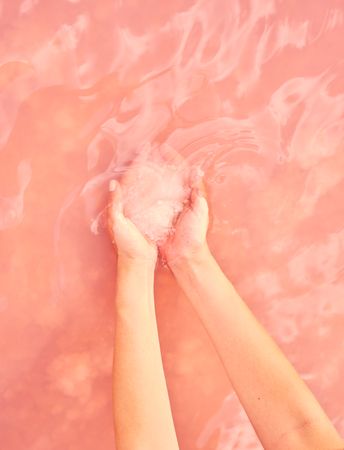 Female holding healing salt pile in pink water