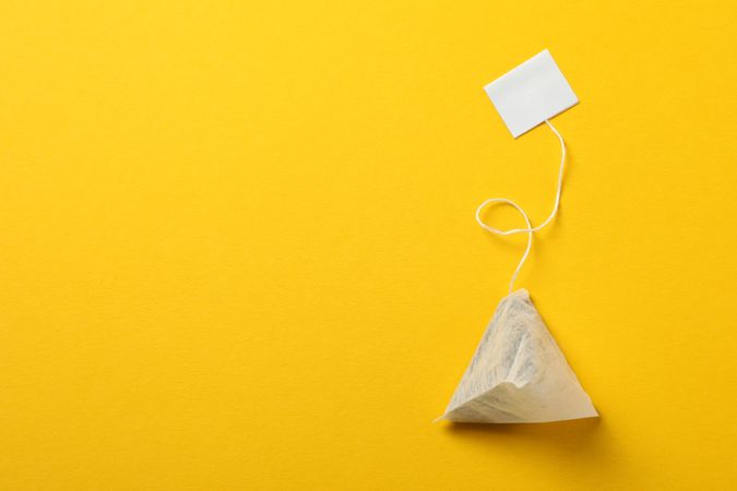 Tea bag with label on yellow background, space for text
