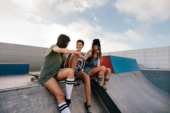 Three women hanging out at skate park giving a fist bump