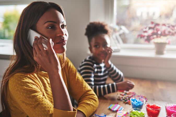 Mother taking call on cell phone while daughter looks on bored