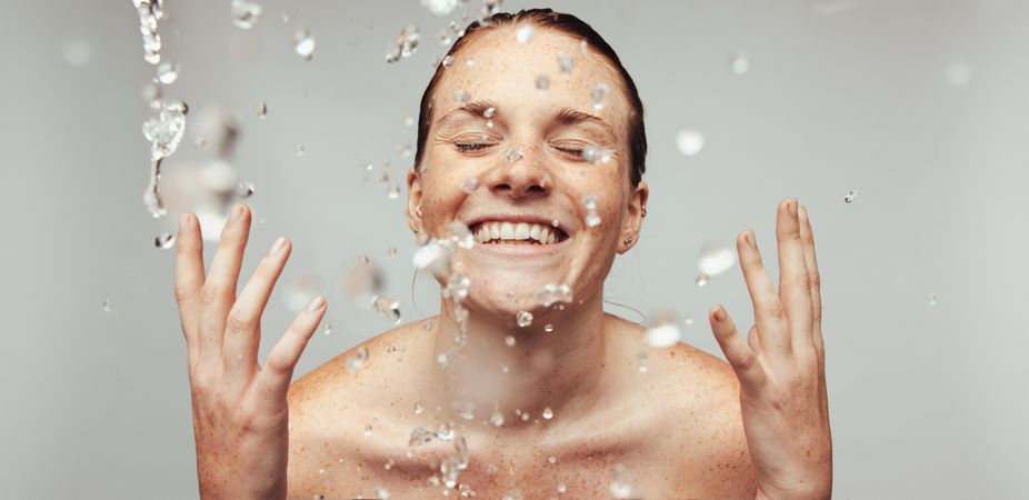 Happy woman splashing water on face