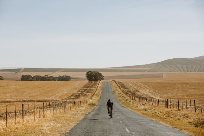 Male athlete cycling on empty road