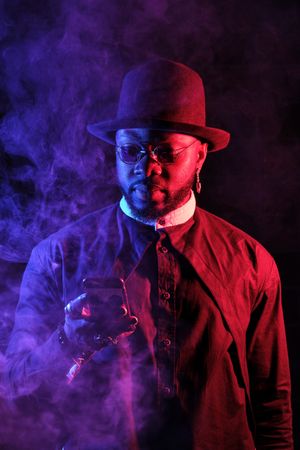Stylish Black male with mobile phone in neon lights