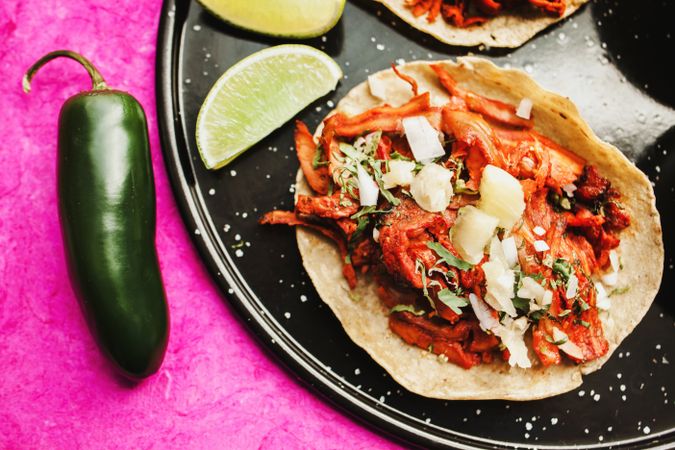 Pepper and lime near tacos al pastor and sauces