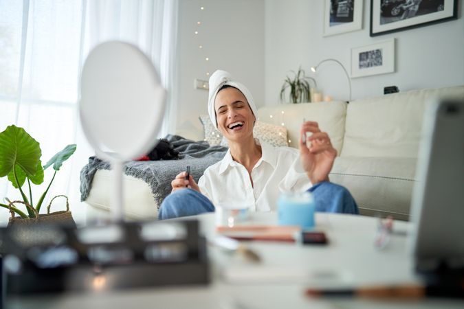 Laughing woman doing makeup at home
