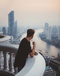 Man on balcony viewing Bangkok in haze