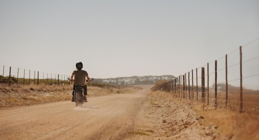 Rear view of man riding motor cycle on a country road
