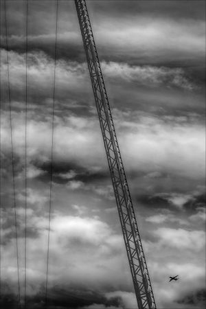 Grayscale photo of crane under cloudy sky