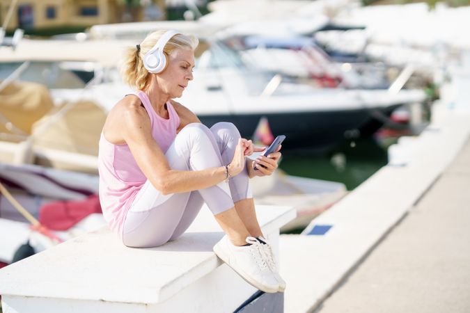 Mature female in athletic clothing texting on waterfront