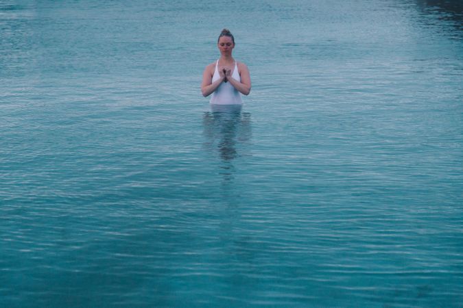 Woman in pool near sea and hills on shore