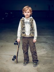 Child with skateboard standing on street