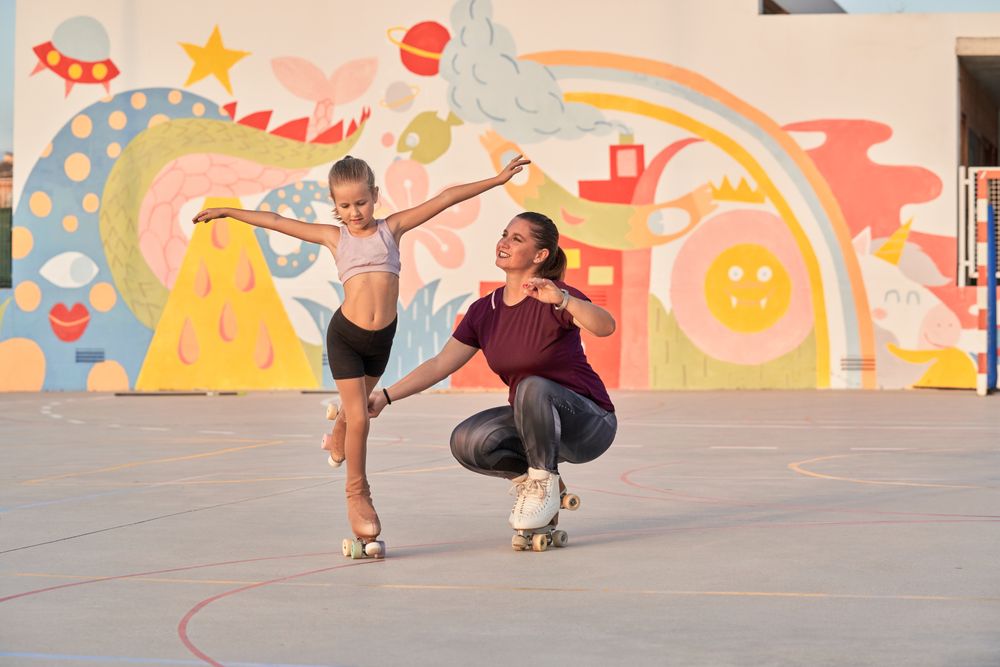 Woman helping girl to do exercise on roller skates