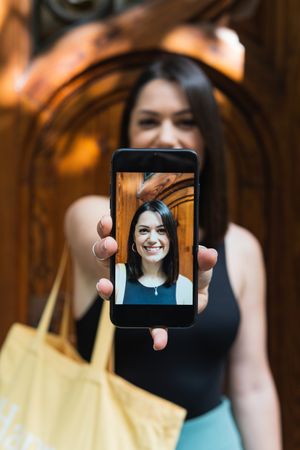 Delighted woman taking selfie on smartphone in city