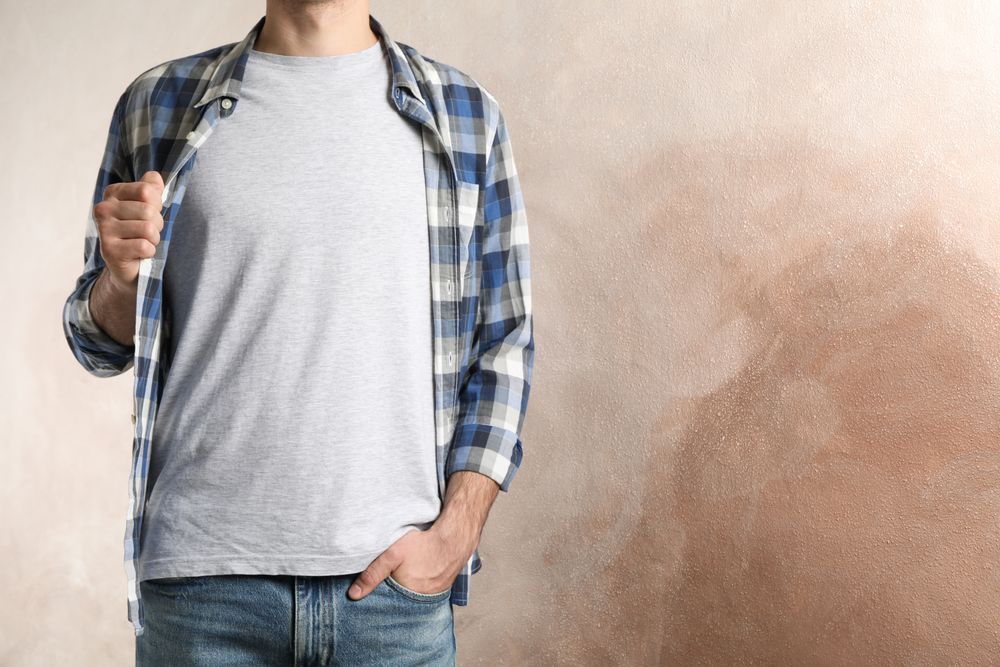 Men in grey t-shirt and checkered shirt against brown background, copy space