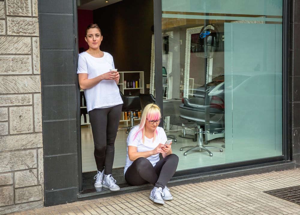 Hair stylists taking break outside door of salon