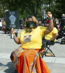 Woman holding Black Power fish with raised fist, Washington, D.C.