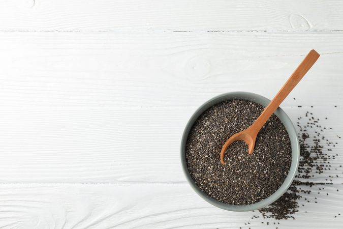 Chia seeds, wood spoon and bowl on wooden background, copy space