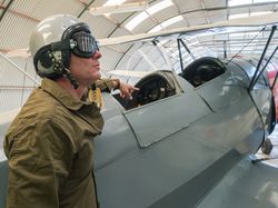 Confident pilot beside retro plane in hangar